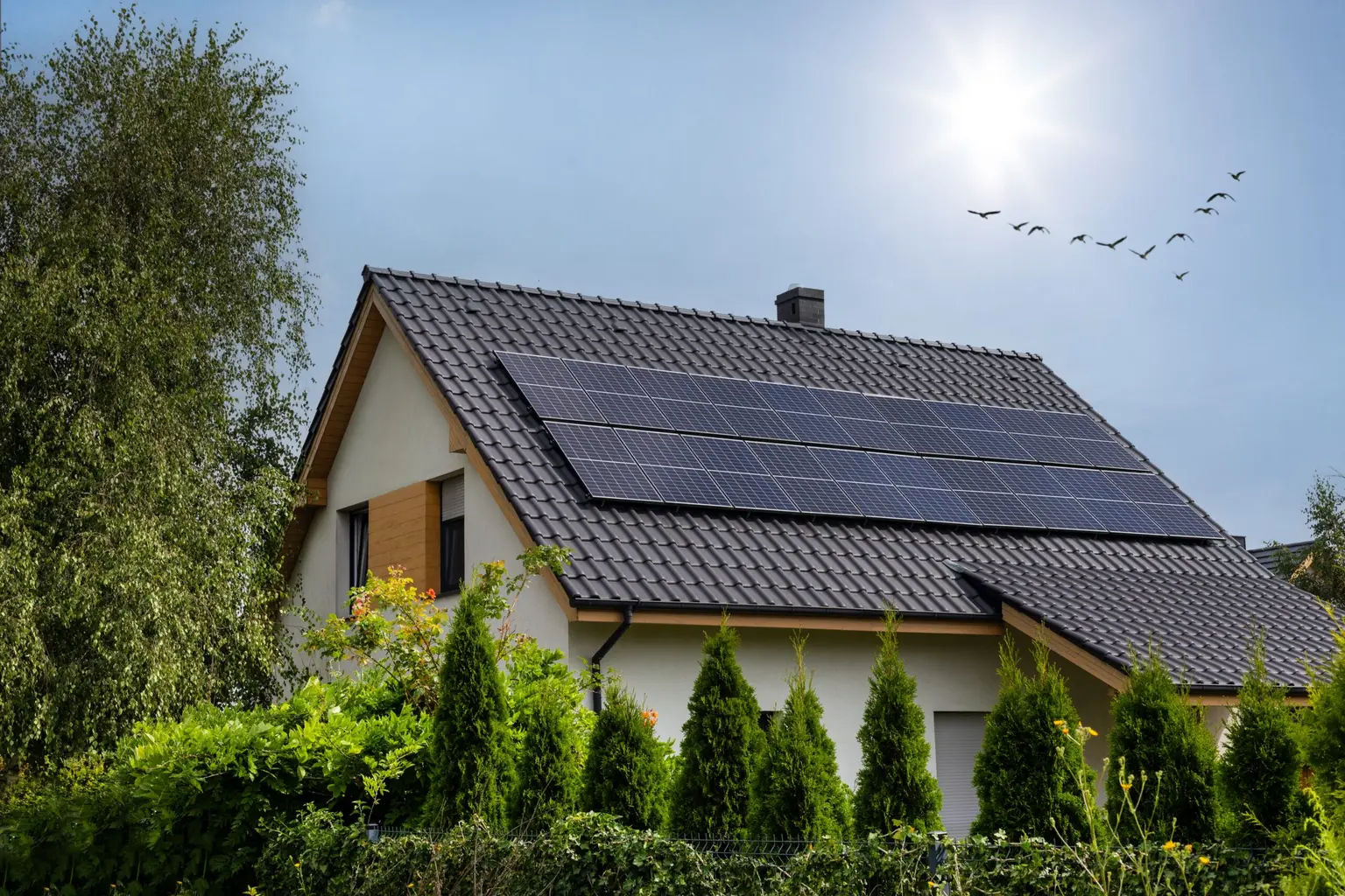 Two rows of solar panels on the tiled roof of a family home under full sun
